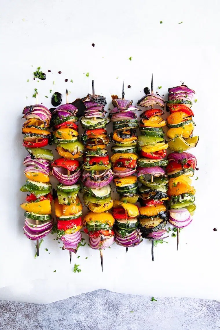 white surface with six colorful veggie skewers made with zucchini, bell pepper and onion
