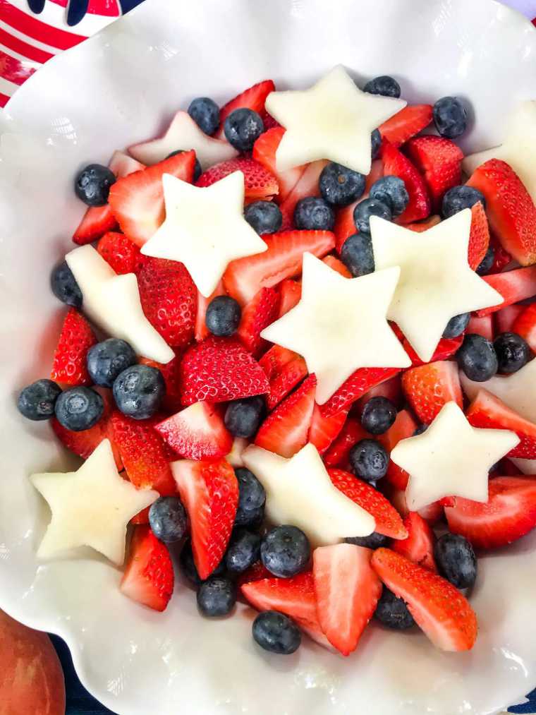 white bowl of patriotic red white blue berry peach fruit salad
