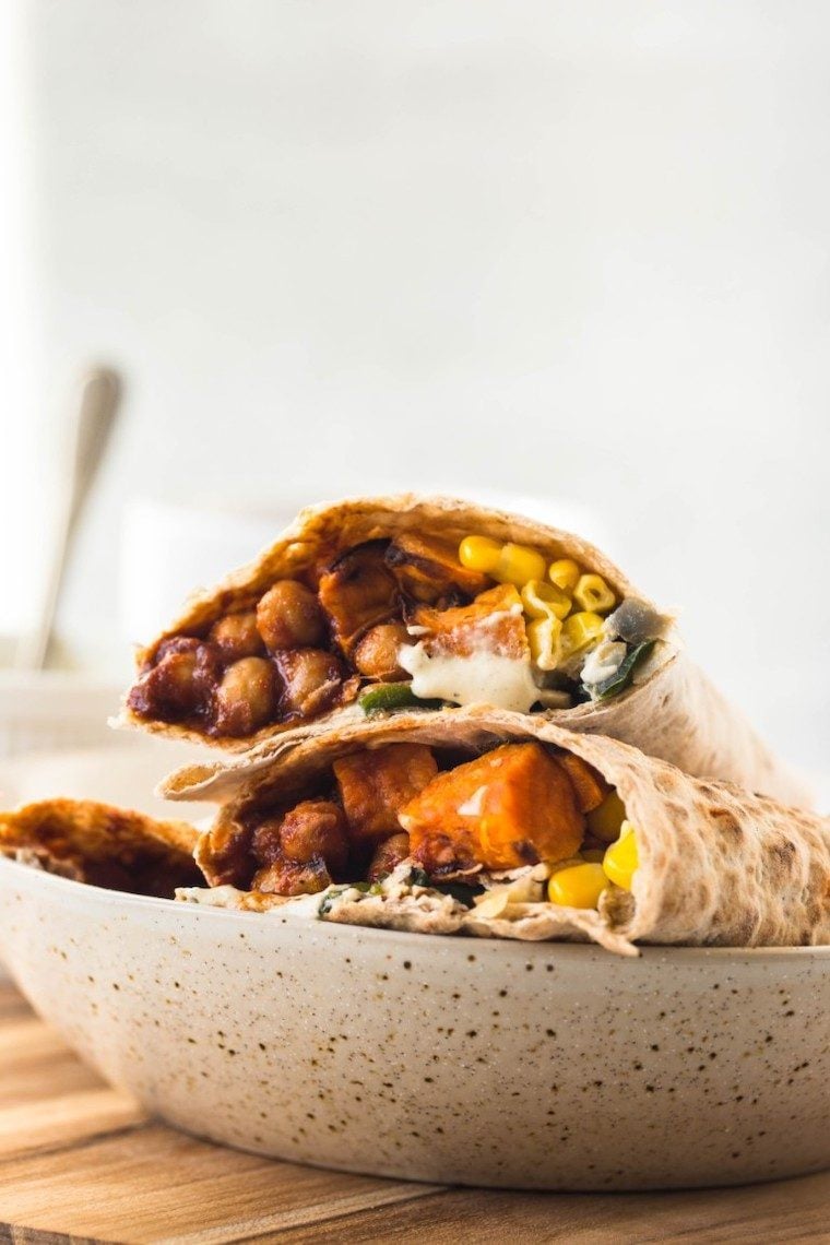 white speckled plate with two vegan wraps on it that are filled with sweet potato, chickpeas and corn