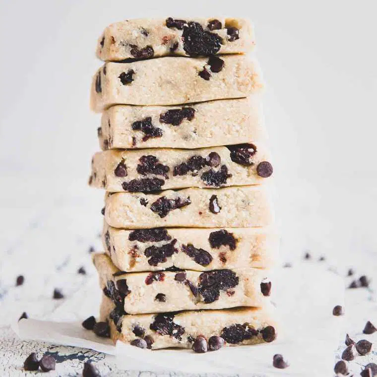 white surface with eight stacked no-bake vegan cookie dough bars with chocolate chips