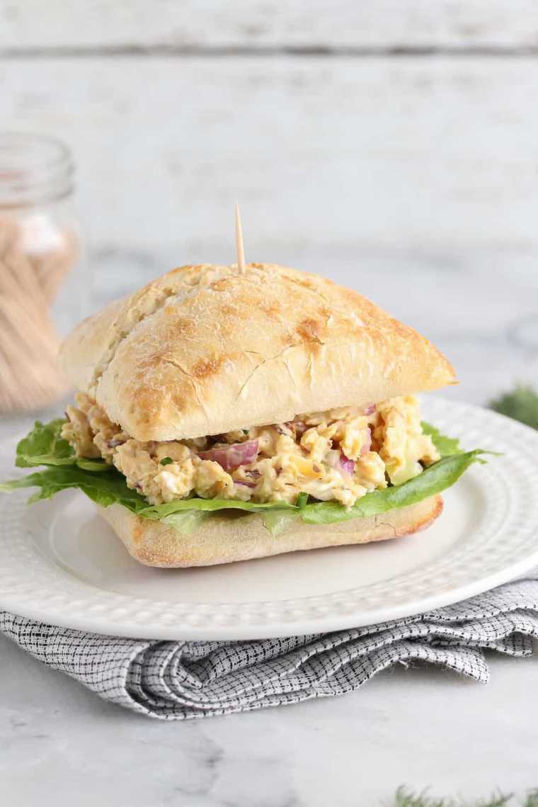 white plate on a table with a vegan chicken salad sandwich