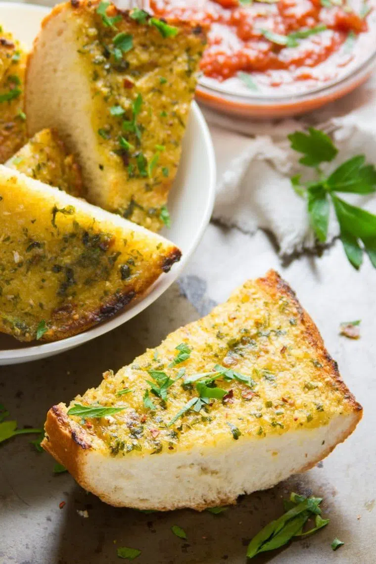 several slices of freshly baked vegan garlic bread with olive oil and herbs
