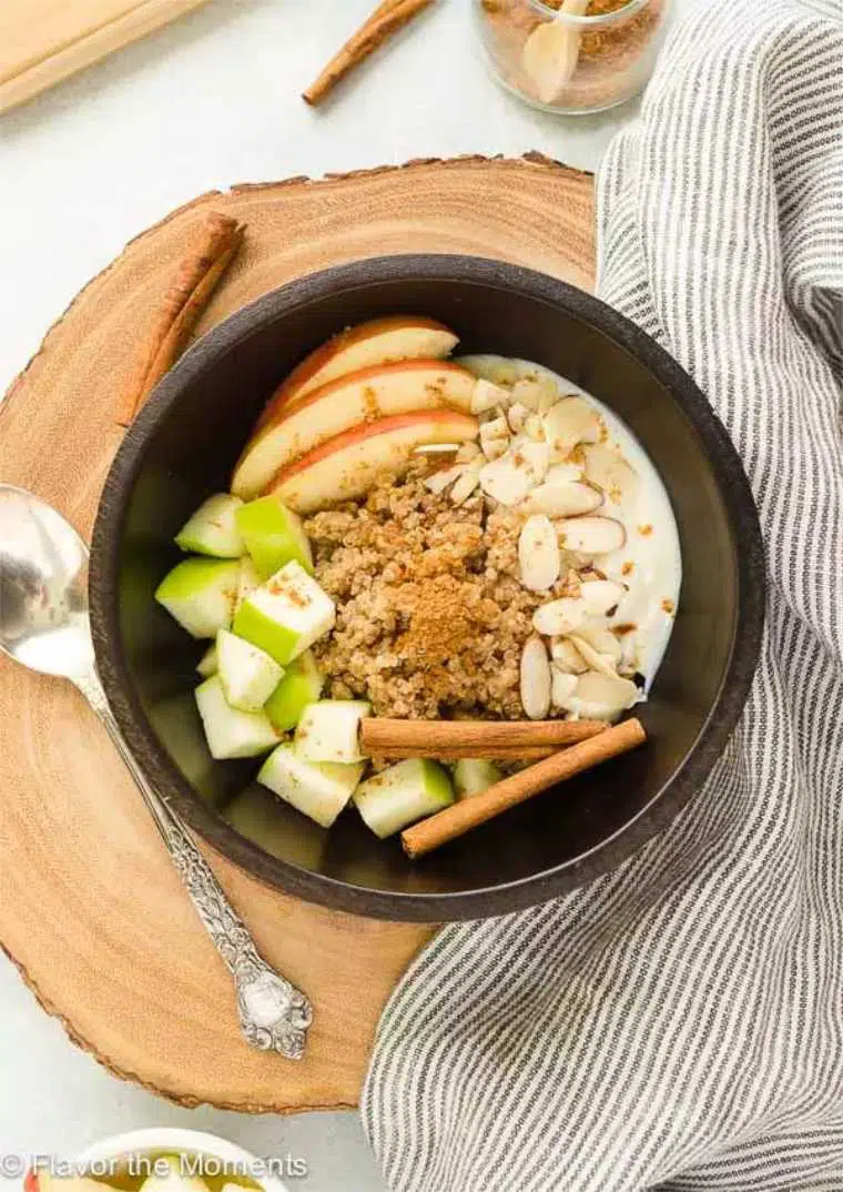 black bowl with cooked quinoa, chai spices, apple and almonds
