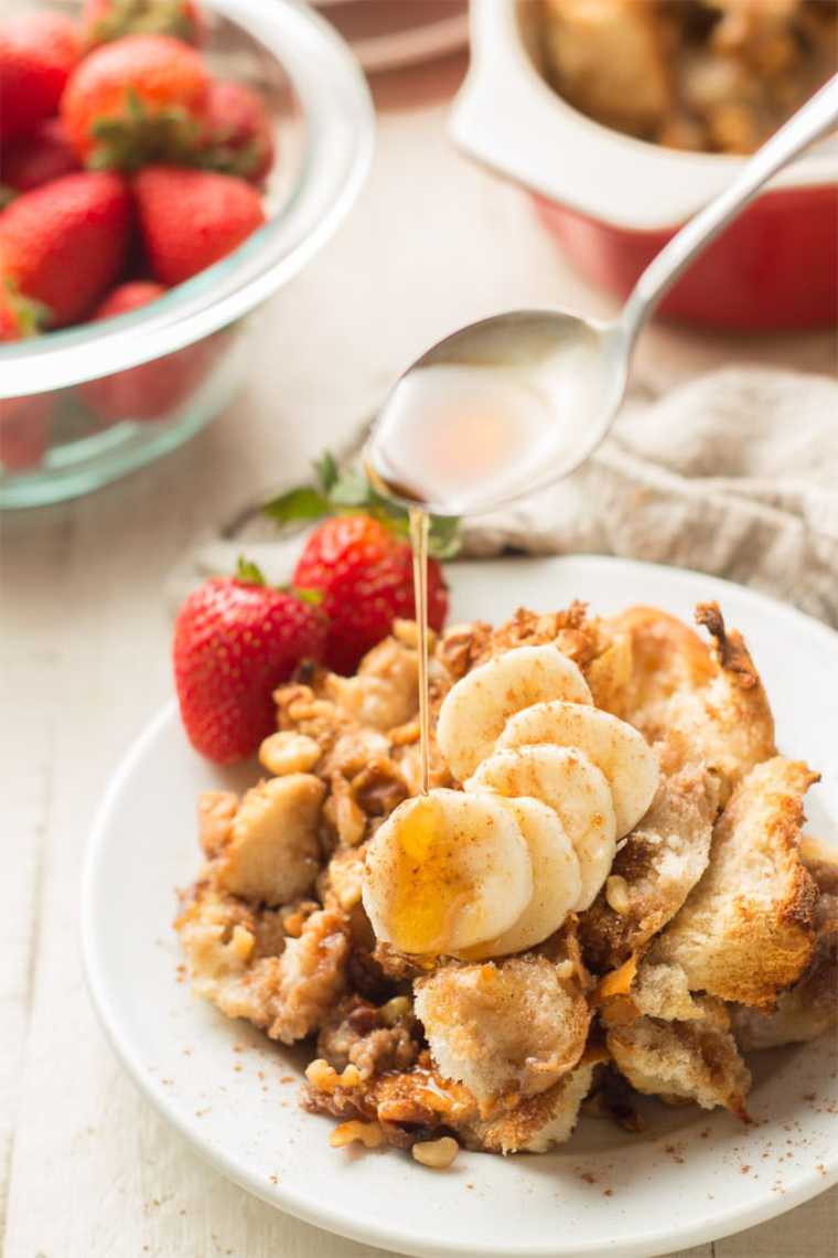 white plate with vegan french toast casserole, banana and strawberries