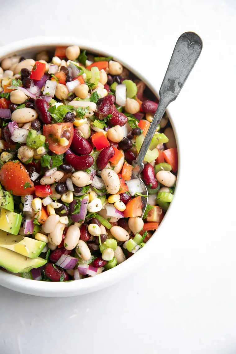 white bowl with loaded bean salad featuring tomatoes, onion and avocado