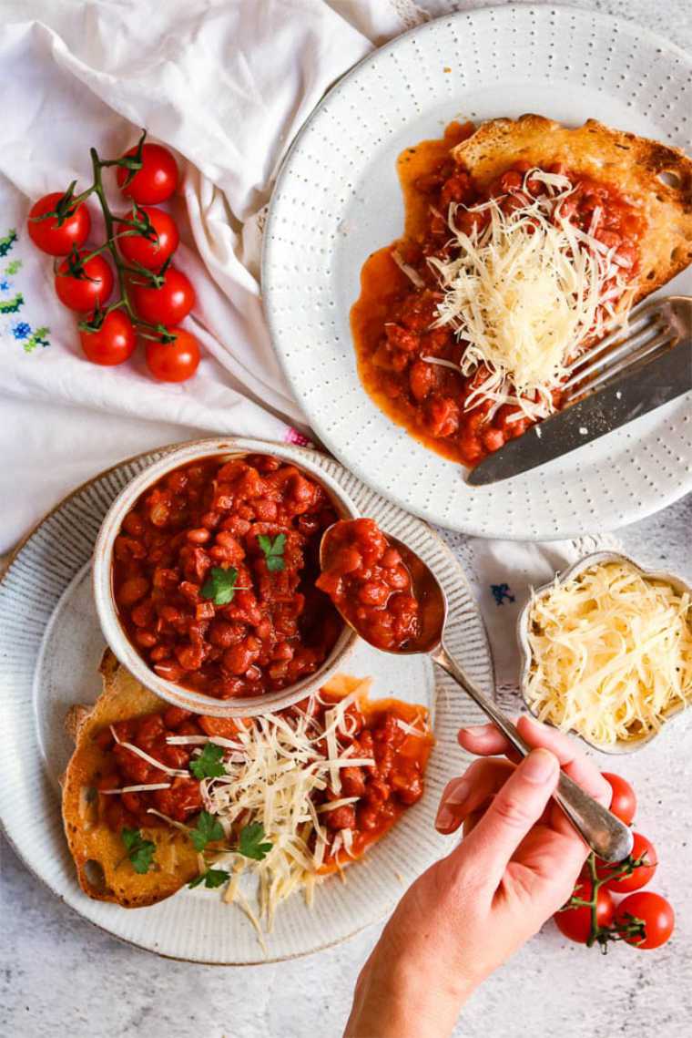 two white plates on a table with vegan baked beans and toasted bread
