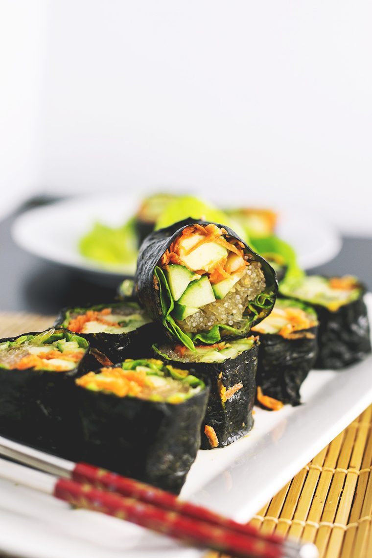 white plate with 9 rolls of raw vegan sushi filled with vegetables and kelp noodles