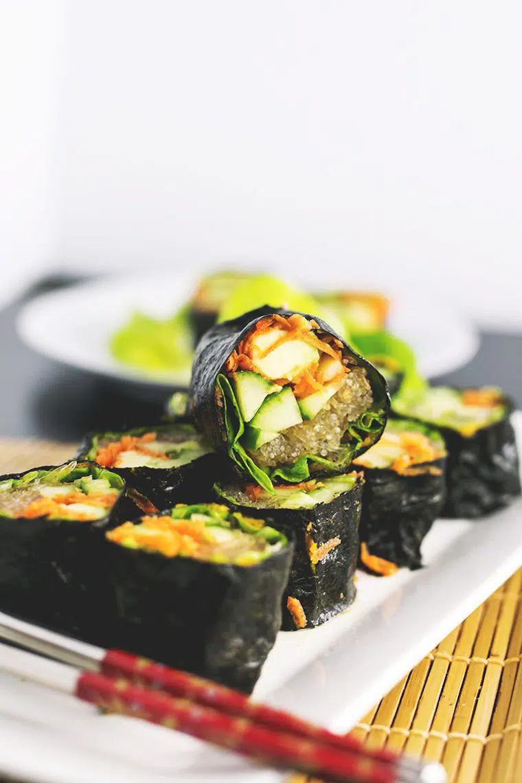 white plate with 9 rolls of raw vegan sushi filled with vegetables and kelp noodles