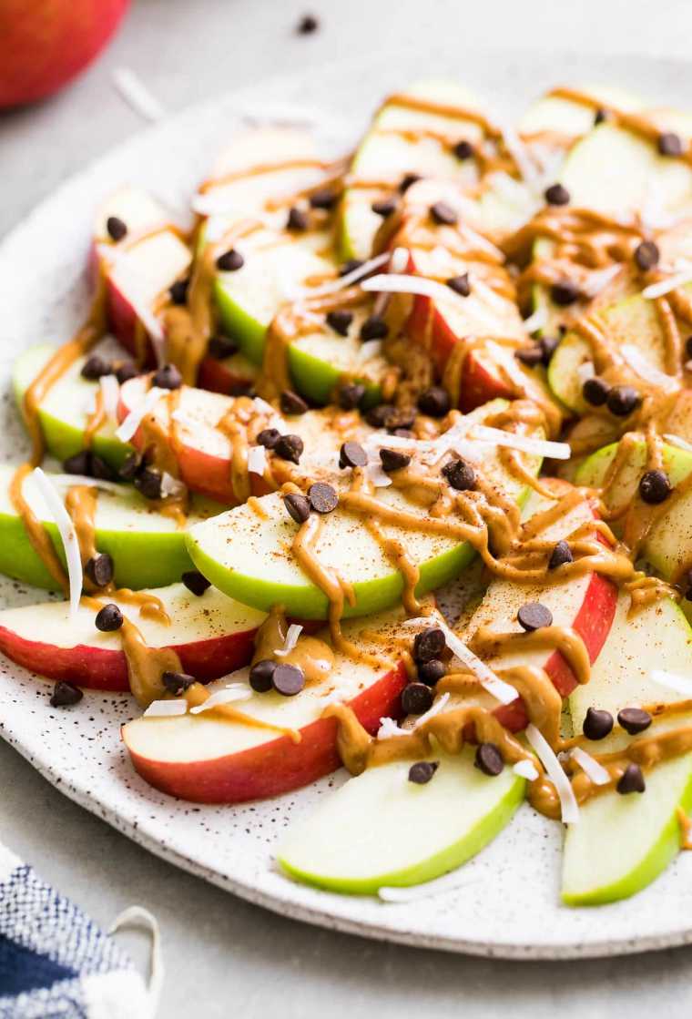white plate with sliced apples, peanut butter and chocolate chips
