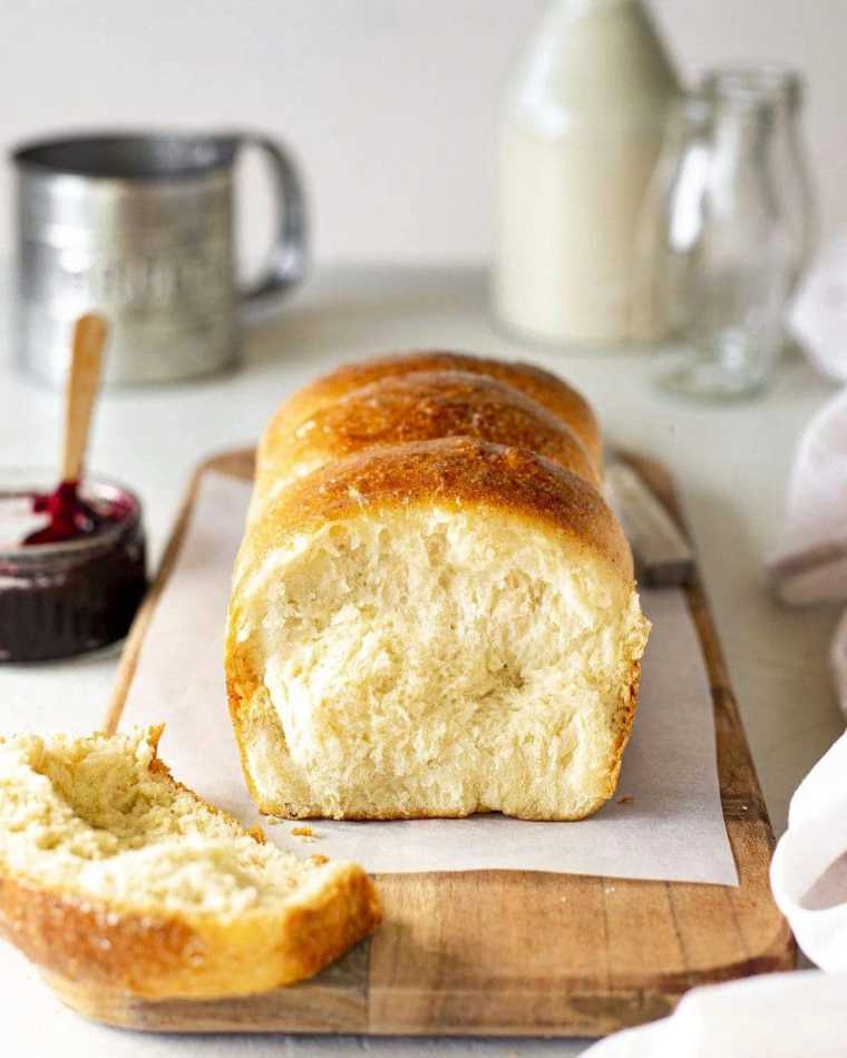white table with jam and a cutting board with homemade fluffy vegan brioche