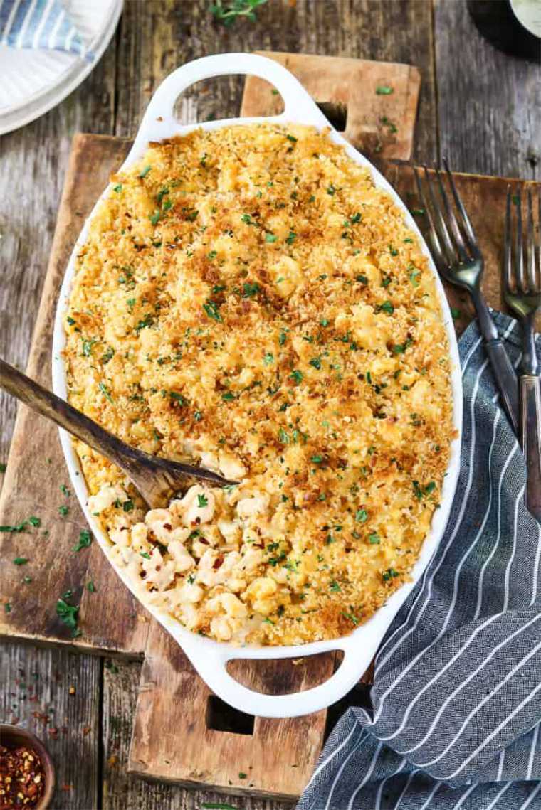 large white dish with baked vegan mac and cheese and a wooden spoon