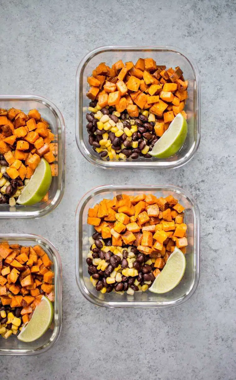four glass containers with sweet potato cubes, black beans, corn and lime