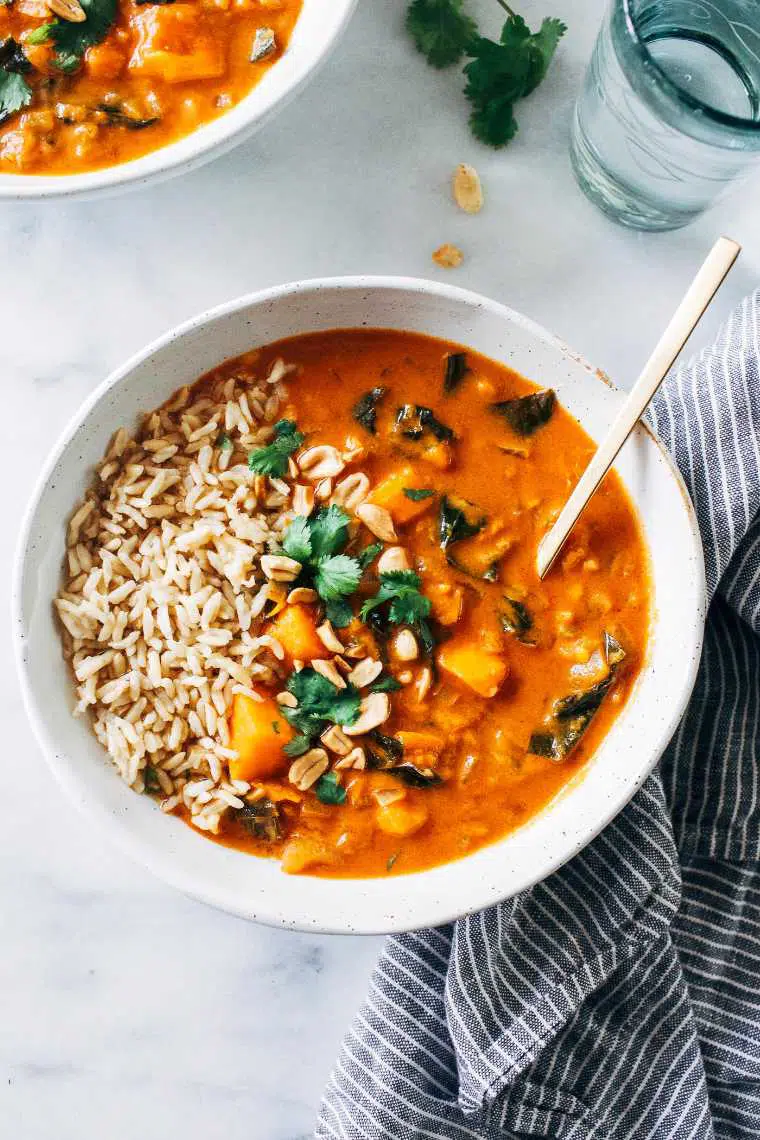 white bowl with plant-based African peanut stew, rice and a spoon