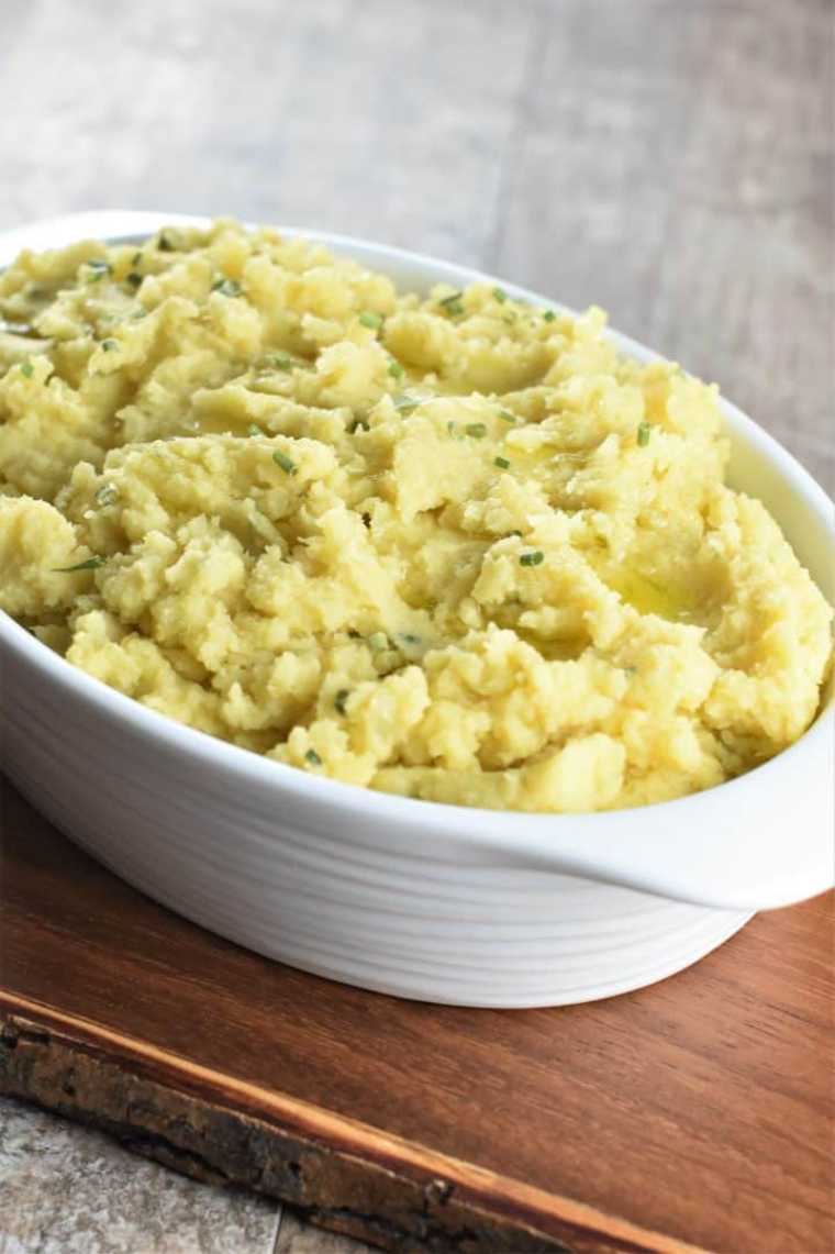white serving bowl with Cheesy Vegan Mashed Potatoes