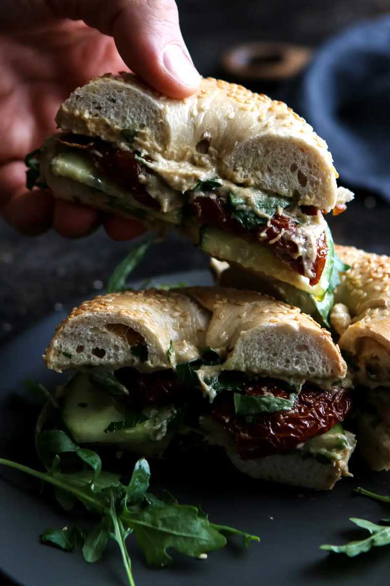 several halved Vegan Bagel Sandwiches with sun dried tomatoes on a plate