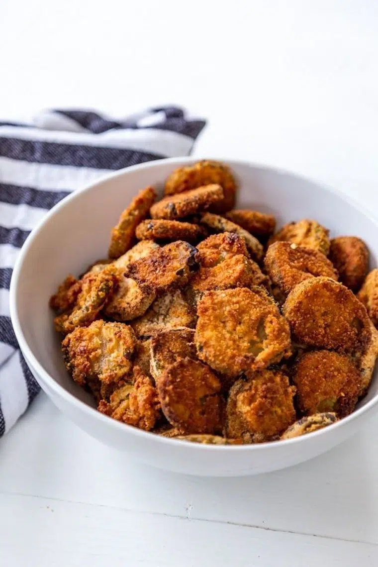 white bowl on a table which is filled with a traditional southern vegan soul food: healthy air fried pickles