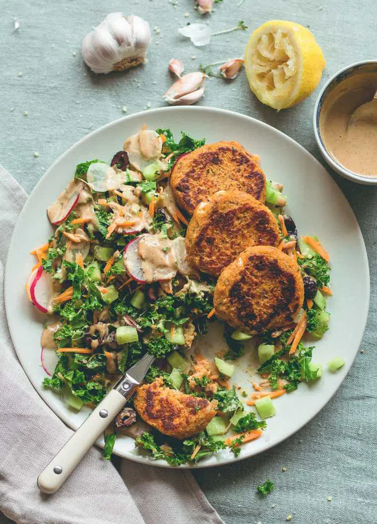 plate with green salad and four vegan sweet potato quinoa patties