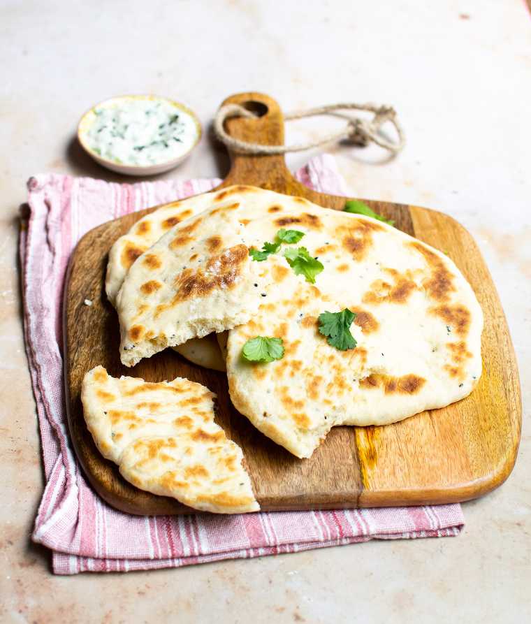 chopping board with several homemade vegan naan bread pieces