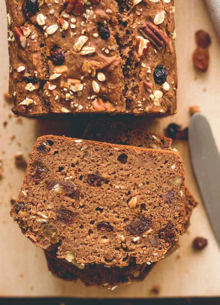 close up of spiced Christmas bread with nuts and dried fruit next to a knife