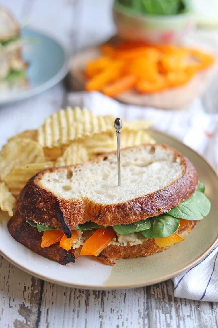 a veggie-stuffed jalapeno cashew cheese vegetable sandwich with potato chips on a plate