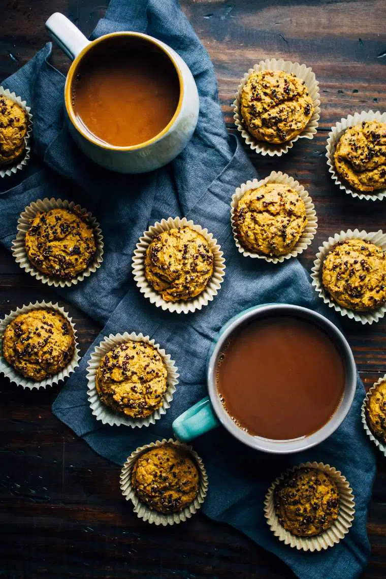 wooden table with a dozen savory quinoa muffins next to two large cups of coffee