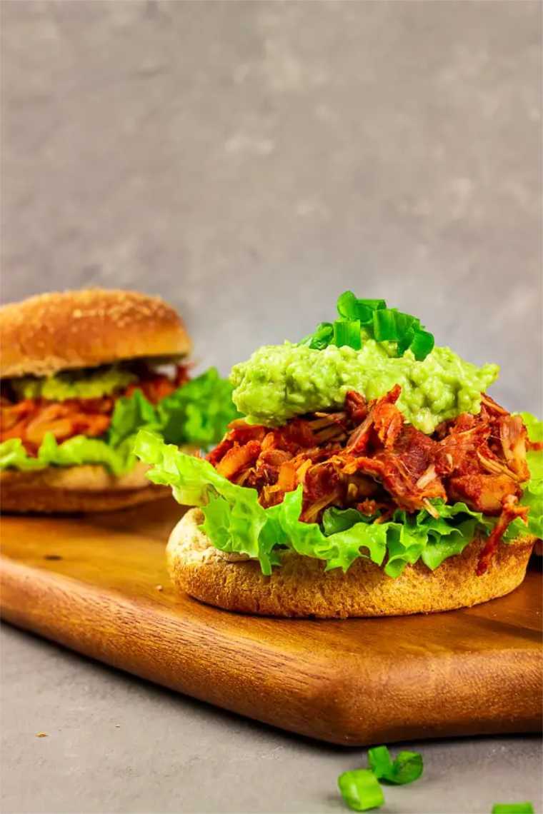 two vegan pulled pineapple bbq jackfruit burgers on a chopping board