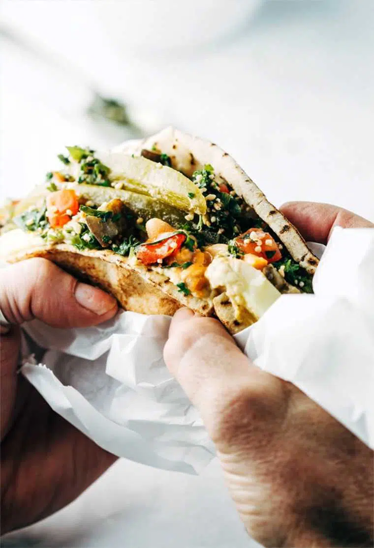 close up of two hands holding a homemade vegan sabich sandwich for lunch