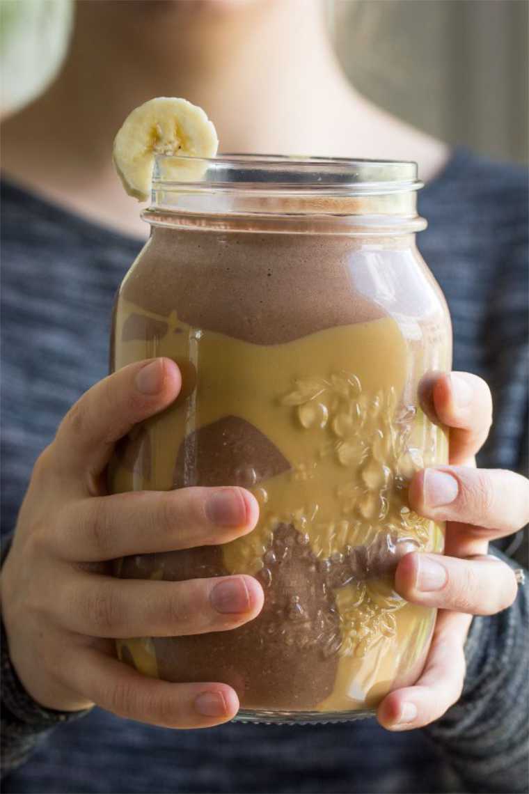 person holding a large glass of Peanut Butter Chocolate Smoothie in both hands
