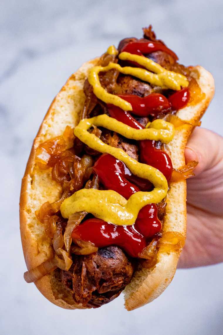 close up of a bund with a veggie sausage, mustard and ketchup as a vegan 4th of July recipe idea