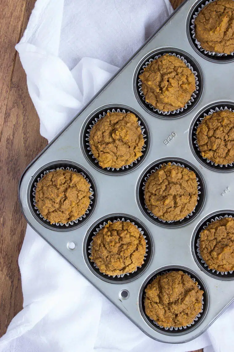 Vegan Pumpkin Muffins in tray standing on a white towel and wooden table