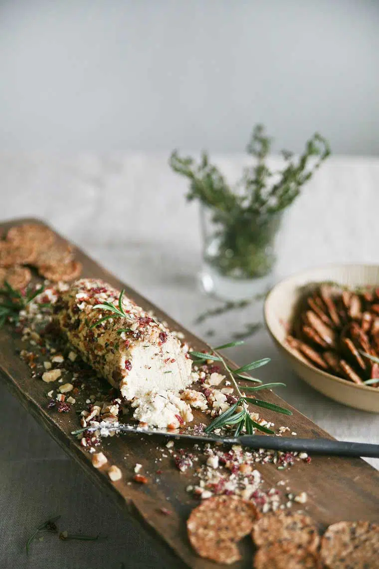 roll of homemade rosemary Nut Cheese on a chopping board