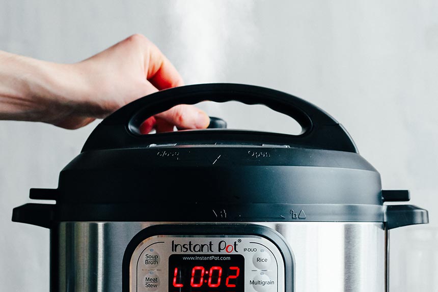 the electric pressure cooker instant pot being ready to release steam by hand moving the valve