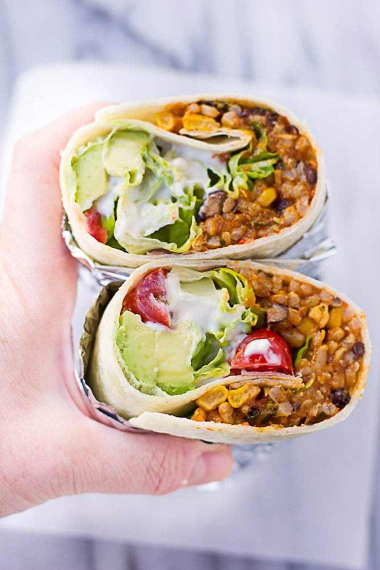 Instant Pot hand holding two homemade vegan instant pot burritos with avocado, rice and beans