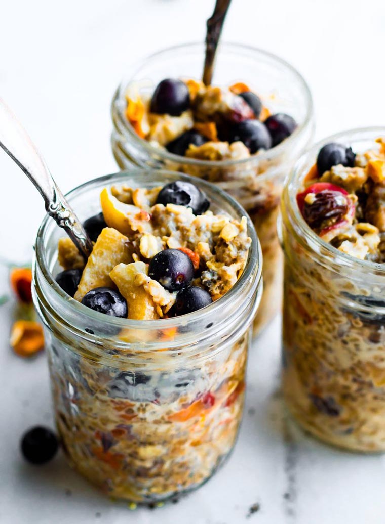 three glass jars with colorful oatmeal, berries and nuts
