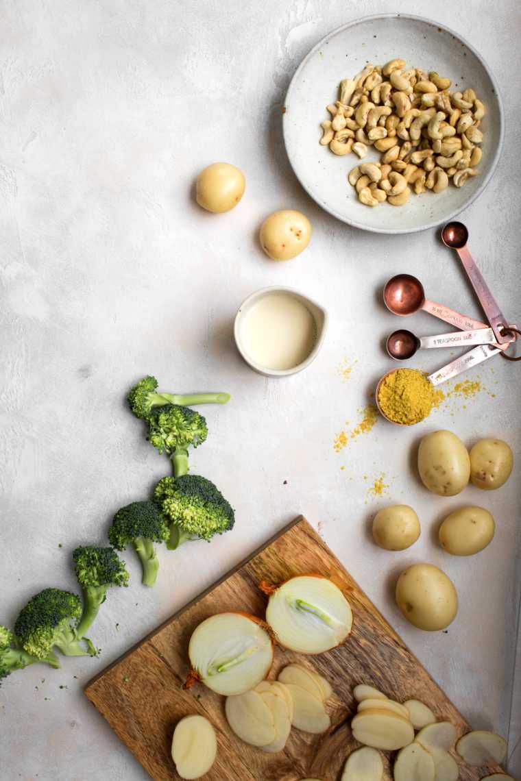 table with broccoli florets, potatoes, cashews and different spices