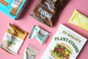 7 kinds of different vegan packaged snacks lying on pink surface