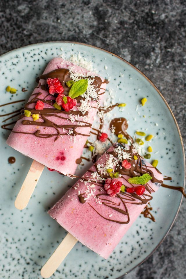Top view of two Raspberry Coconut Smoothie Popsicles sprinkled with toppings on a light blue plate