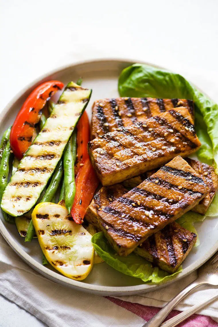 white plate with grilled zucchini, beans, bell pepper and marinated tofu