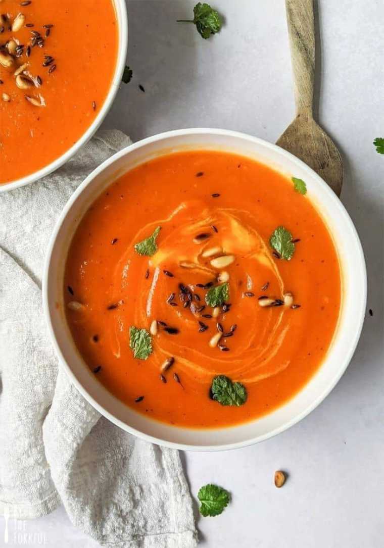 two white bowls with vibrantly red roasted pepper and butternut squash soup