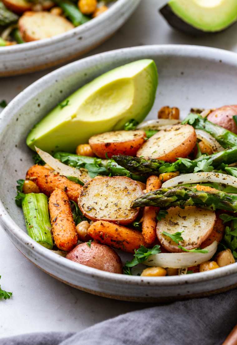 large grey bowl with baked carrot, asparagus, potato, onion and fresh avocado