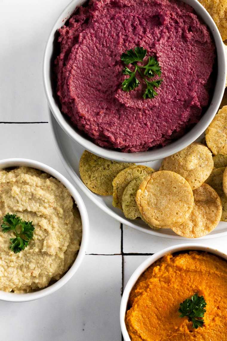 three different-colored low fodmap hummus variations and some crackers
