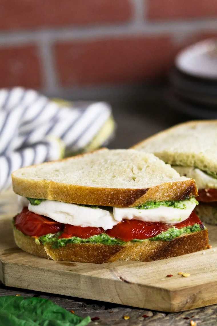 wooden cutting board with two vegan roasted red pepper sandwiches