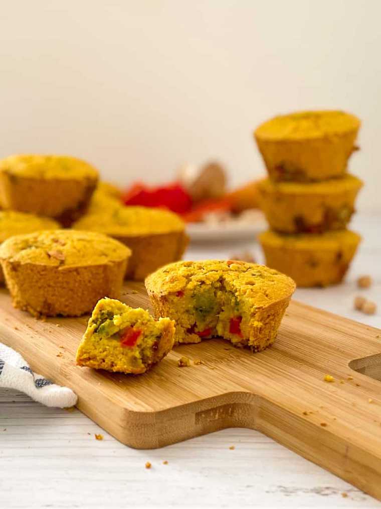 wooden cutting board with two vegan frittata muffins and more behind them on a table