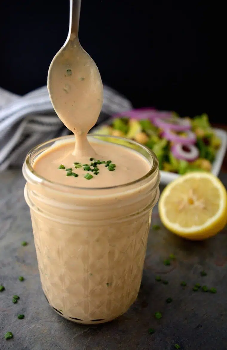 glass jar with some creamy vegan BBQ ranch dressing which is dripping from a spoon