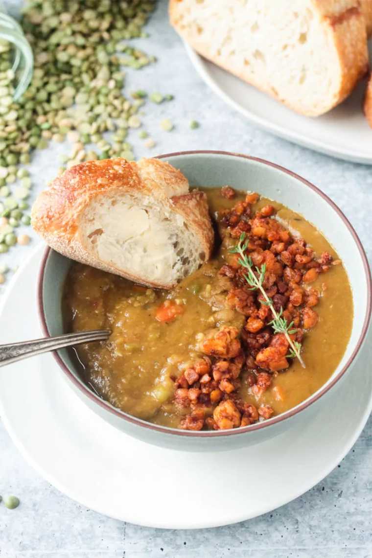 table with fresh bread and a bowl of creamy vegan split pea soup