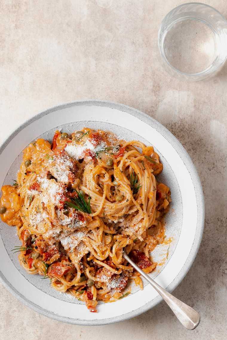white plate on a table with spaghetti in a creamy sundried tomato sauce