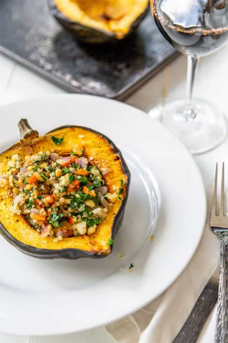 white plate with half an acorn squash that was baked and stuffed with quinoa and veggies