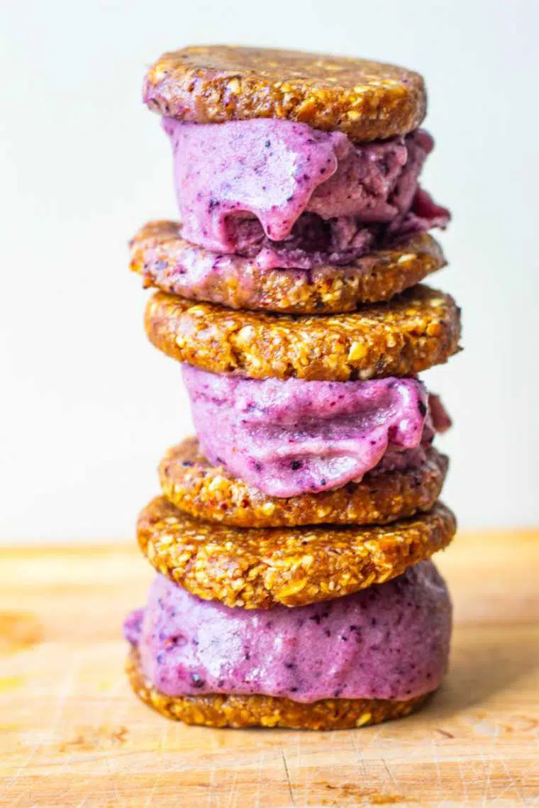 wooden surface with three Raw Vegan Blueberry Ice Cream Sandwiches on top of each other
