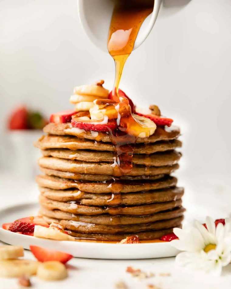 huge stack with Kid-Friendly Vegan Pancakes on a plate being drizzled with maple syrup