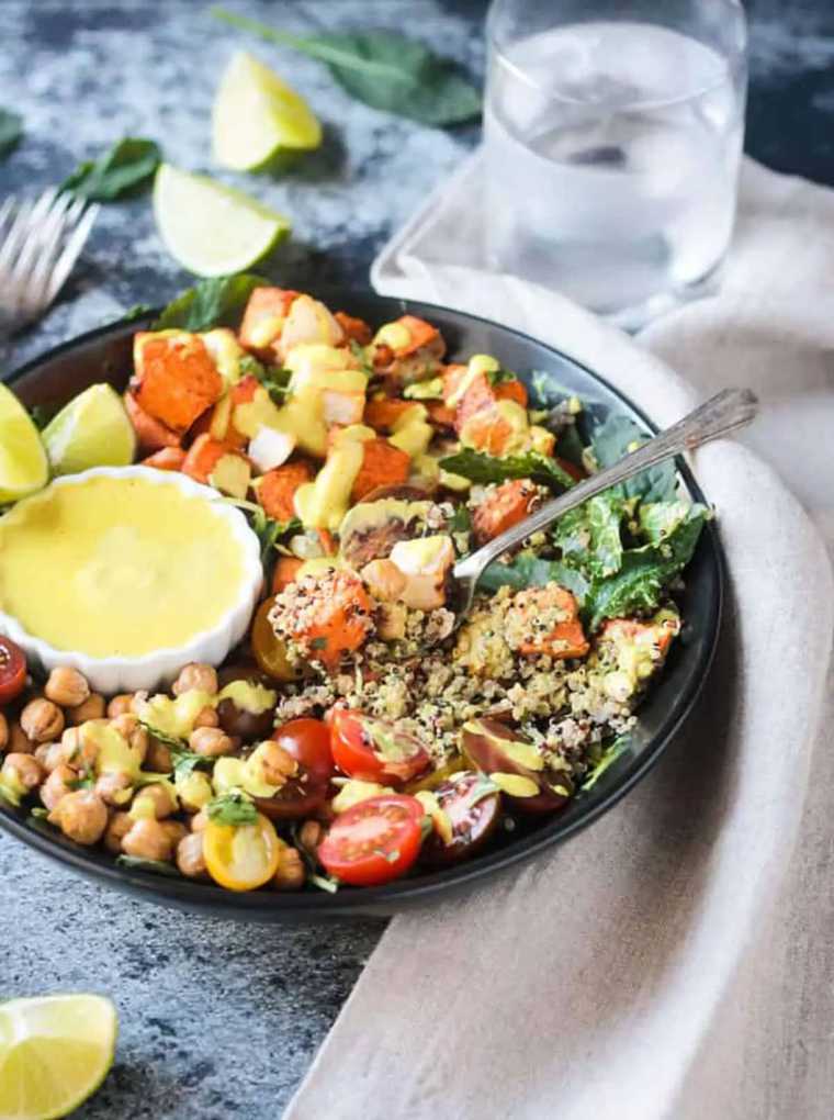 black bowl with quinoa, beans, tomatoes, leafy greens and roasted vegetables